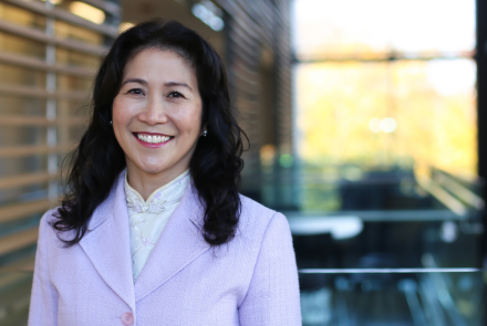 headshot of Melinda Fleming smiling at the camera in a lavendar suit jacket, dark hair styled long and loose