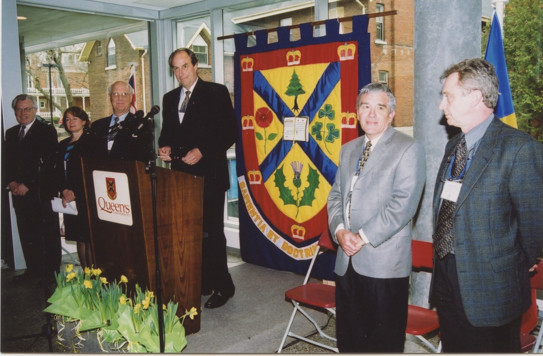 QCRI Founders and Queen's Health Sciences Leadership standing in front of a podium inside the new building.