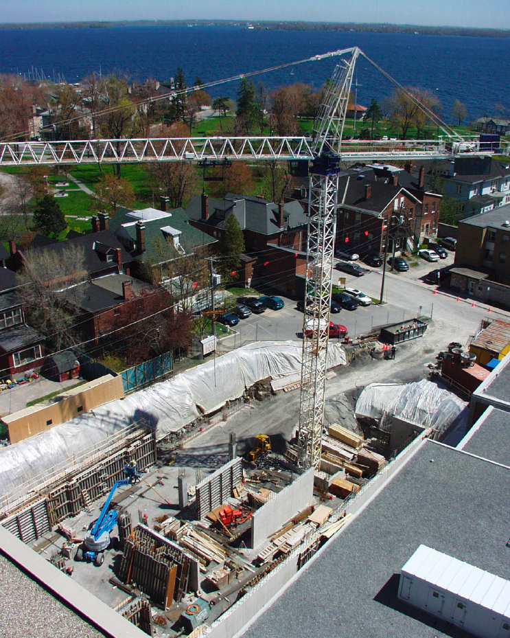 Aerial view of the construction site behind Botterell Hall, with a large crane and excavation pit in the foreground and Lake Ontario visible in the background. Photo by Dr. Roger Deeley.