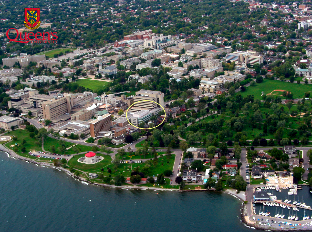 Aerial photograph taken from an airplane showing the completed Queen’s Cancer Research Institute building within a broad view of the surrounding Queen’s University campus.