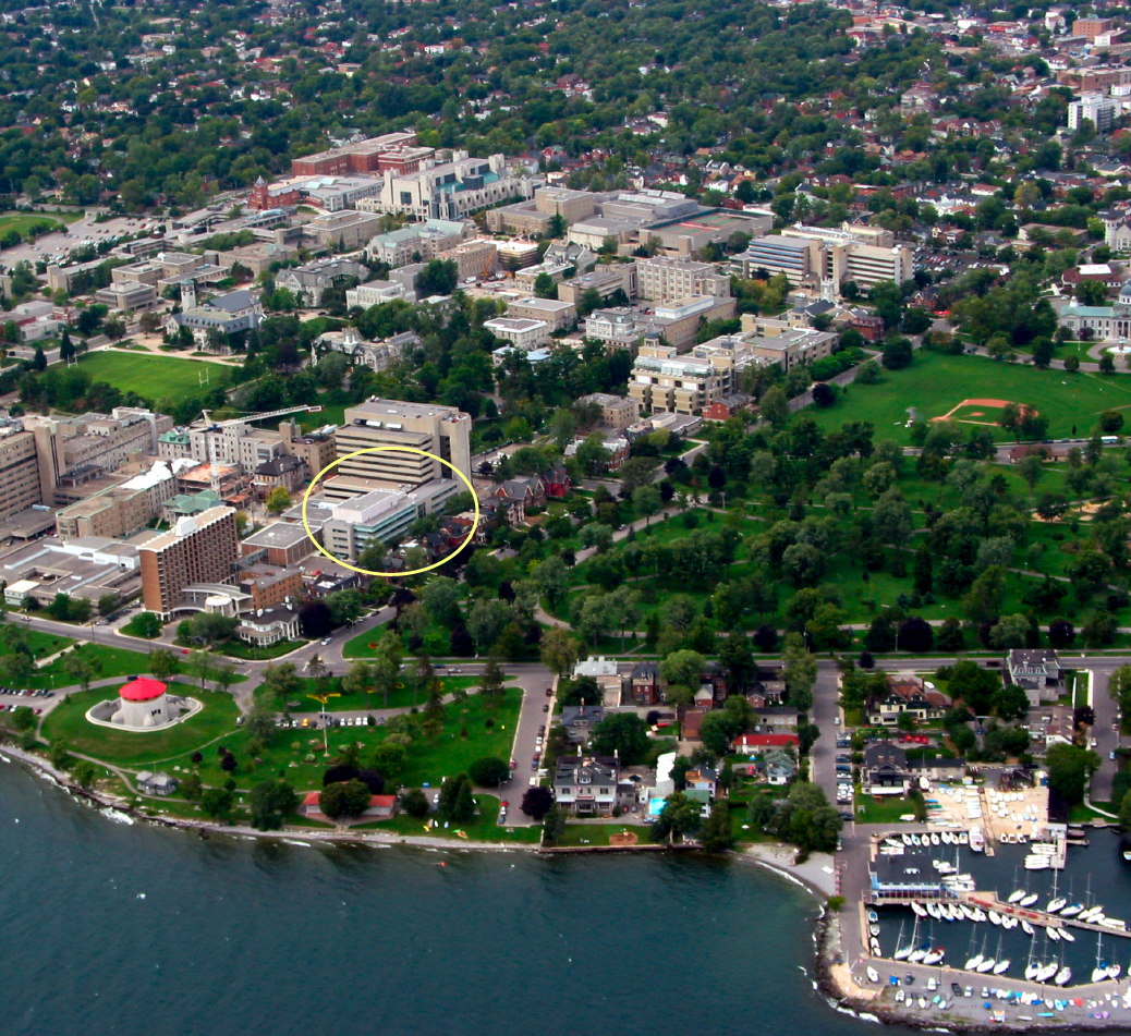 Aerial photograph taken from an airplane showing the completed Queen’s Cancer Research Institute building within a broad view of the surrounding Queen’s University campus.