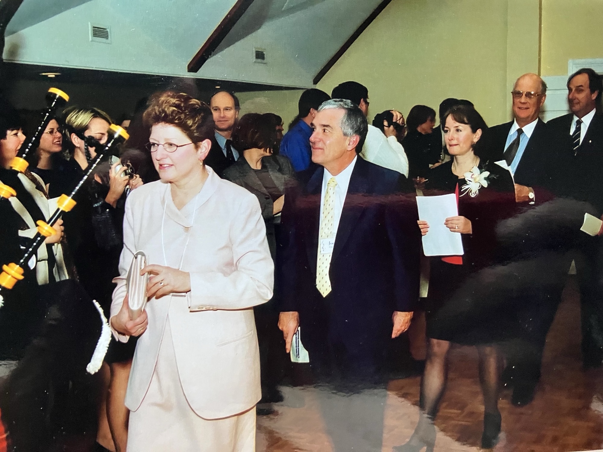  A procession during the 2002 dedication ceremony for the Eisenhauer Chair in Clinical Cancer Research, with Elizabeth Eisenhauer, Carla Eisenhauer and Joe Pater among those participating. Audience members watch, applaud and take photographs.