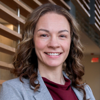headshot of Jamaica Cass smiling into the camera wearing a grey jacket and burgundy top