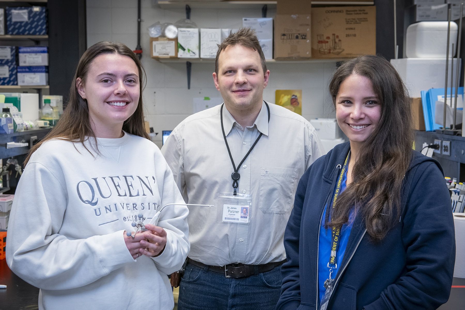 Kaytlin Andrews, James Purzner and Teresa Purzner holding the new surgical tool they invented, smiling at the camera