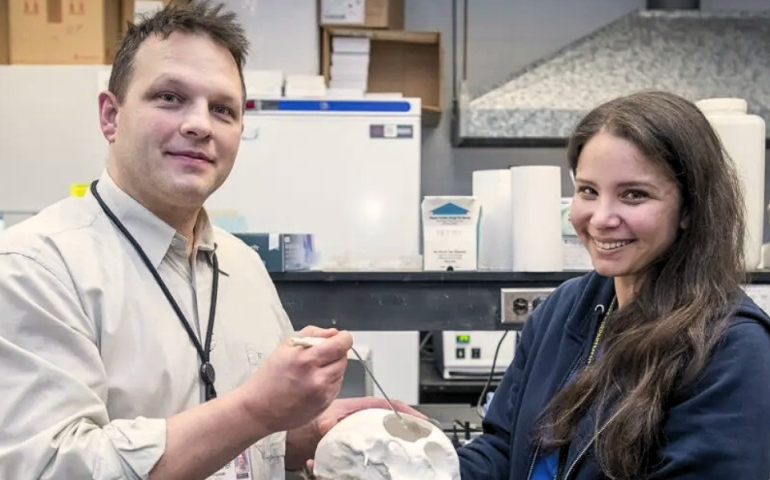Drs. James and Teresa Purzner smiling and presenting their new medical tool with a model skull to indictate how it will be used during surgical procedures