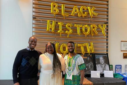 three Black medical students stand in front of Black History Month display