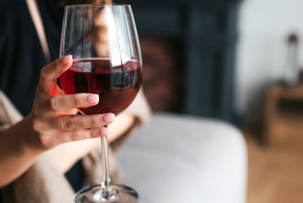 close up photo of someone holding a glass of red wine