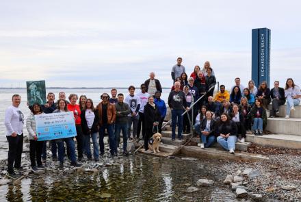 SCRI researchers gather at Richardson Beach in support of the Terry Fox Run, holding signs of support and poster of Terry Fox