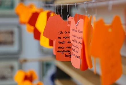orange tshirts cut out in paper for people to write their reconciliation reflections - displayed in the Queen's School of Medicine